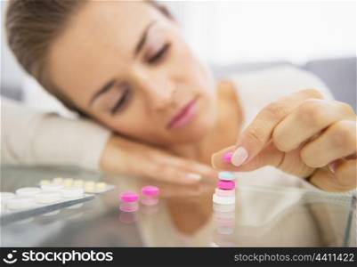 Closeup on frustrated young woman playing with pills