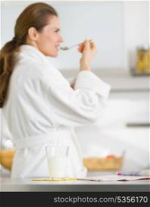 Closeup on glass of milk and magazine on table and young woman in bathrobe in background