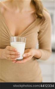 Closeup on glass of milk in hand of young woman