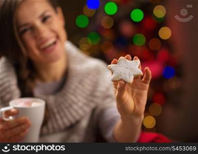 Closeup on hand holding Christmas cookie and happy woman in background