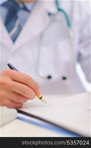 Closeup on hand of medical doctor writing in clipboard