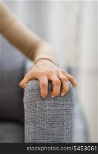 Closeup on hand of stressed woman sitting on sofa