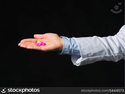 Closeup on hand with tablets isolated on black