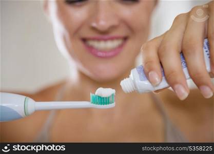 Closeup on hands squeezing toothpaste on electric toothbrush