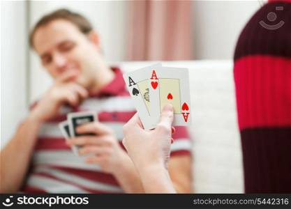 Closeup on hands with playing cards and man in background