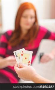 Closeup on hands with playing cards and woman in background
