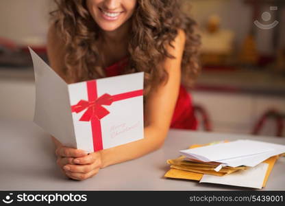 Closeup on happy young housewife reading christmas postcard in kitchen