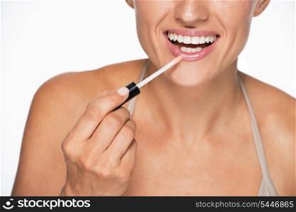 Closeup on happy young woman applying lip gloss