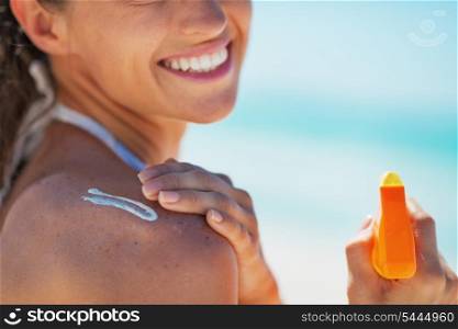 Closeup on happy young woman applying sun block creme
