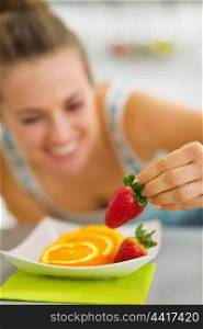 Closeup on happy young woman decorating plate with fruits