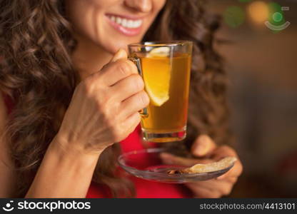 Closeup on happy young woman drinking ginger tea with lemon