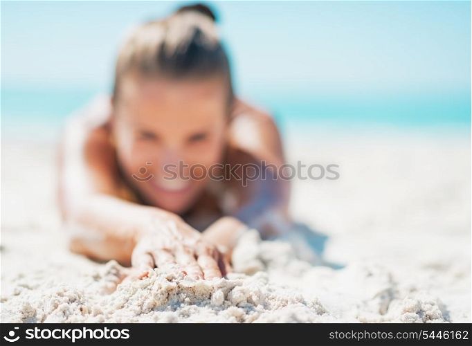 Closeup on happy young woman in swimsuit laying on sandy beach
