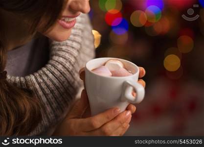 Closeup on hot chocolate with marshmallows in hand of happy woman