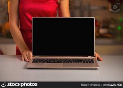 Closeup on laptop blank screen showing by woman in red dress in kitchen