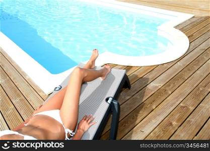 Closeup on legs of woman relaxing in deck chair by pool