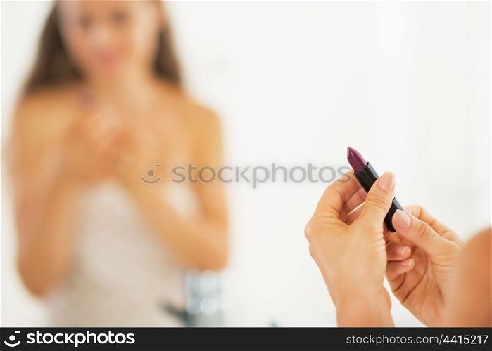 Closeup on lipstick in hand of woman in bathroom