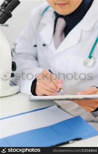 Closeup on male researcher making notes in clipboard