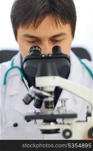 Closeup on medical doctor looking in microscope