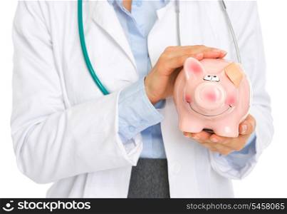 Closeup on medical doctor woman holding piggy bank with patch on ear