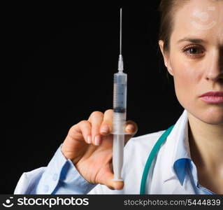 Closeup on medical doctor woman holding syringe isolated on black