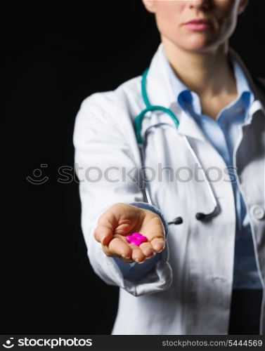 Closeup on medical doctor woman showing pills on black background