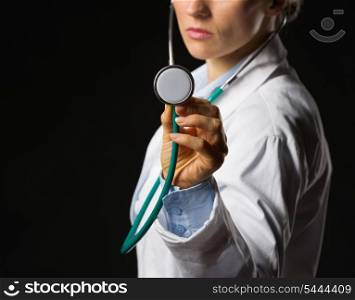 Closeup on medical doctor woman using stethoscope isolated on black