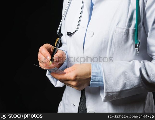 Closeup on medical doctor woman writing prescription on black background