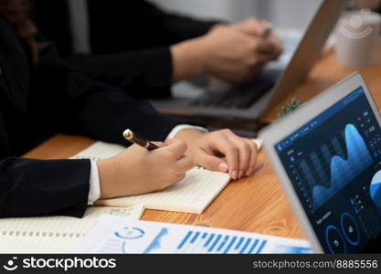 Closeup on meeting desk with businesspeople analyzing business marketing strategy with hands working on laptop display BI dashboard software for analysis team at meeting room of harmony.. Closeup focus on BI dashboard on laptop screen at harmony office.