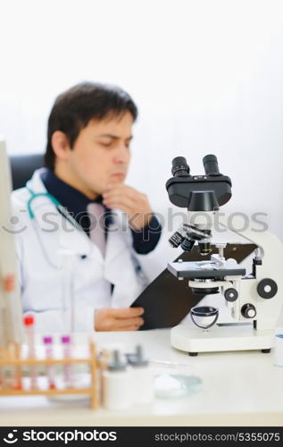 Closeup on microscope and medical doctor in background