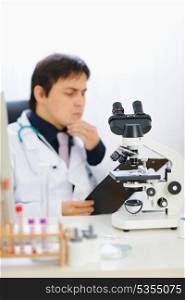 Closeup on microscope and medical doctor in background