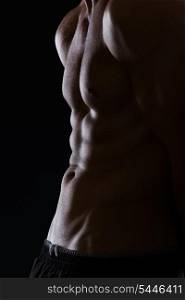 Closeup on muscular male torso with abdominal muscles on black