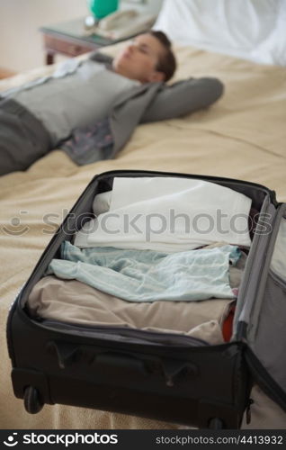 Closeup on open bag and business woman laying in background in hotel room