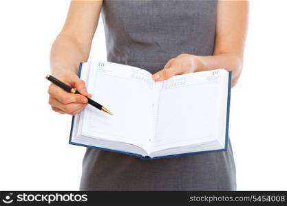 Closeup on pen pointing in open notepad in hands of female