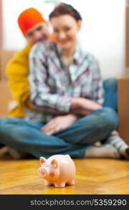 Closeup on piggy bank and young couple in background
