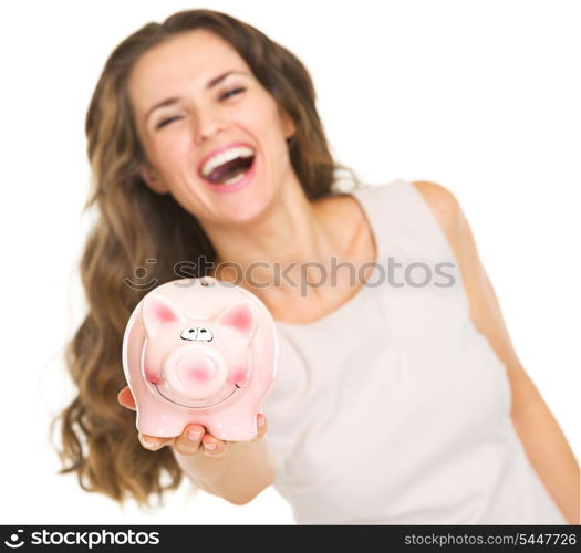 Closeup on piggy bank in hand of smiling young woman