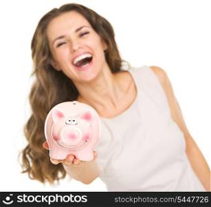 Closeup on piggy bank in hand of smiling young woman