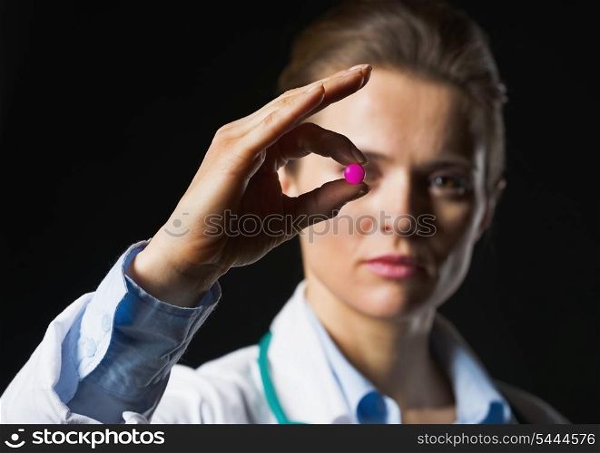 Closeup on pill in hand of doctor woman on black background