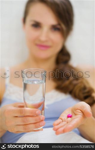 Closeup on pills and glass of water in hand of happy woman
