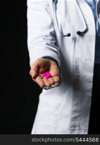 Closeup on pills in hand of doctor woman isolated on black