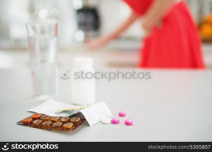 Closeup on pills on table and feeling bad girl in background