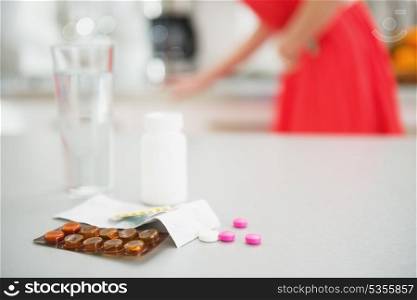 Closeup on pills on table and feeling bad girl in background