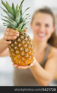 Closeup on pineapple in hand of happy young woman