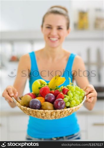 Closeup on plate of fresh fruits giving by smiling young woman
