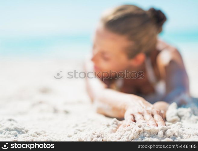 Closeup on relaxed young woman in swimsuit laying on sandy beach