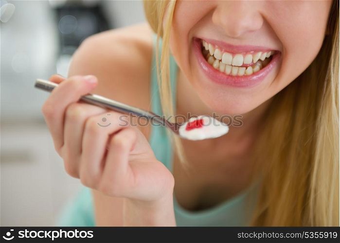 Closeup on spoon with yogurt in hand of smiling teenager girl