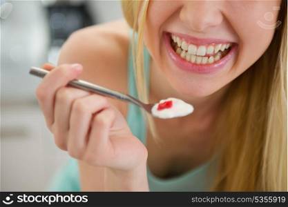 Closeup on spoon with yogurt in hand of smiling teenager girl