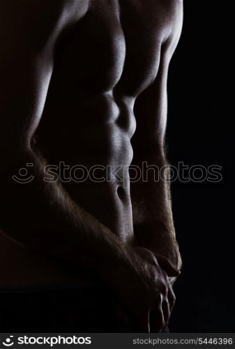 Closeup on sports man showing muscular body on black