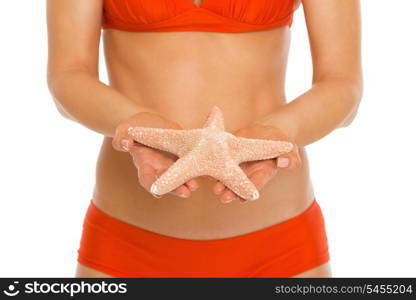 Closeup on starfish in hand of woman in swimsuit