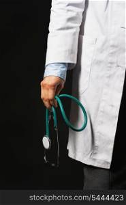 Closeup on stethoscope in hand of doctor woman on black background