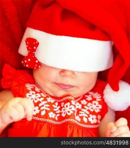 Closeup on sweet adorable newborn baby wearing red Santa hat on the eyes, Christmas celebration, happy wintertime holidays